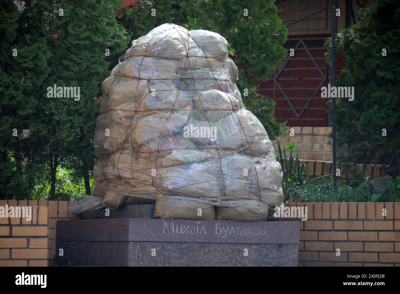 KYIV, UKRAINE - APRIL 11, 2024 - The monument to Mikhail Bulgakov situated on Andriivskyi Descent is sealed from potential damage due to war, Kyiv, capital of Ukraine. Stock Photo