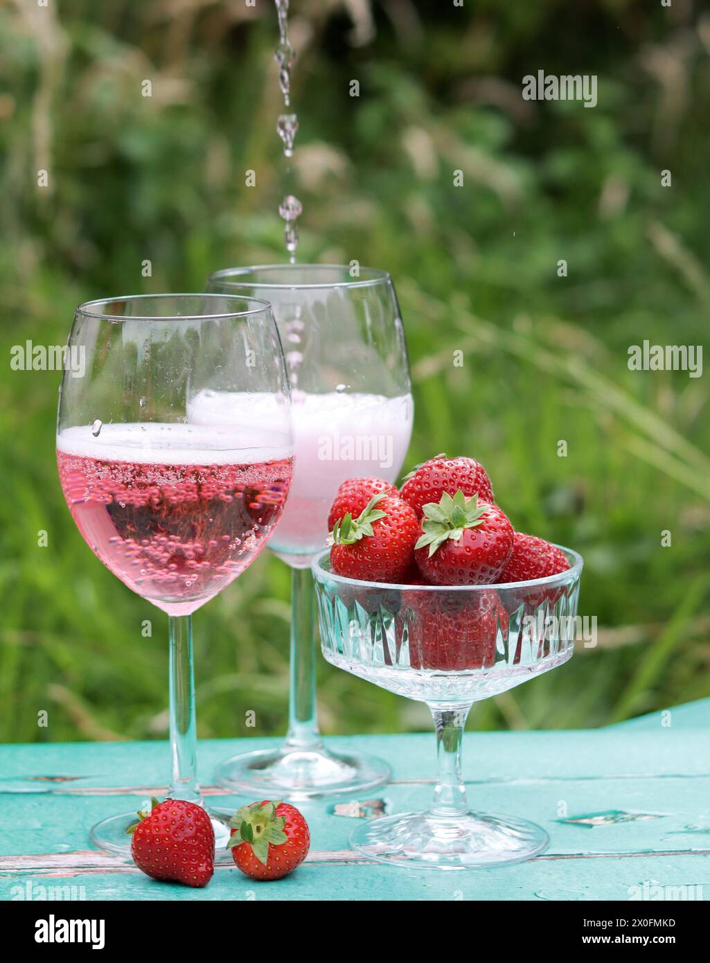 Two glasses of rose sparkling wine and strawberry on a  table. Romantic picnic outdoors. Close up photo of glass tableware. Summer drinks and food. Stock Photo