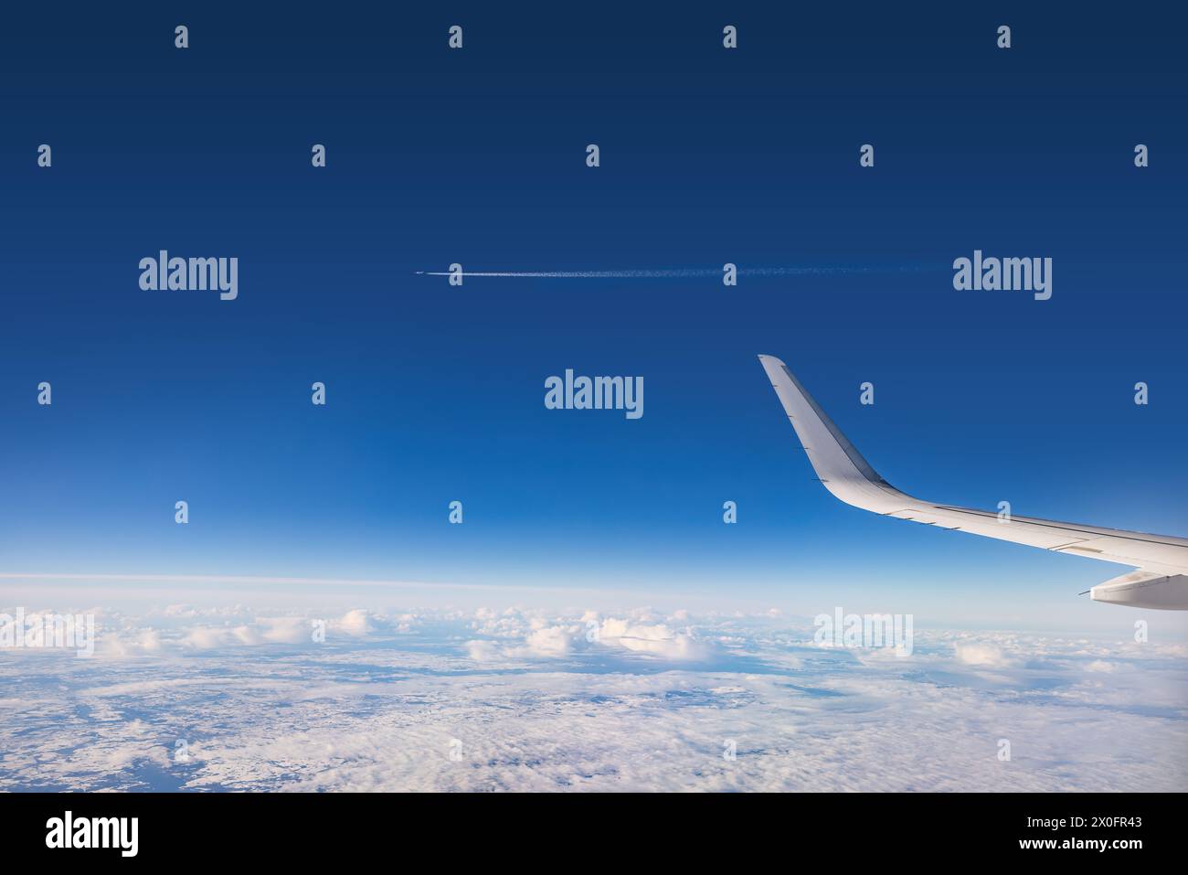 Airplane flying over clouds during on a sunny day Stock Photo