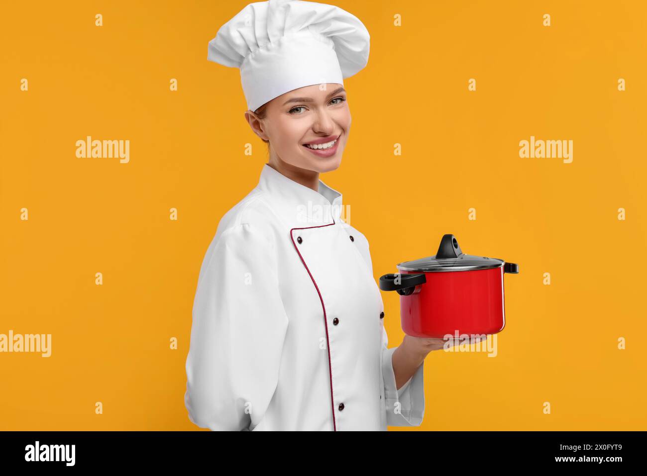 Chef Using Pot Happy chef in uniform holding cooking pot on orange background Stock ...