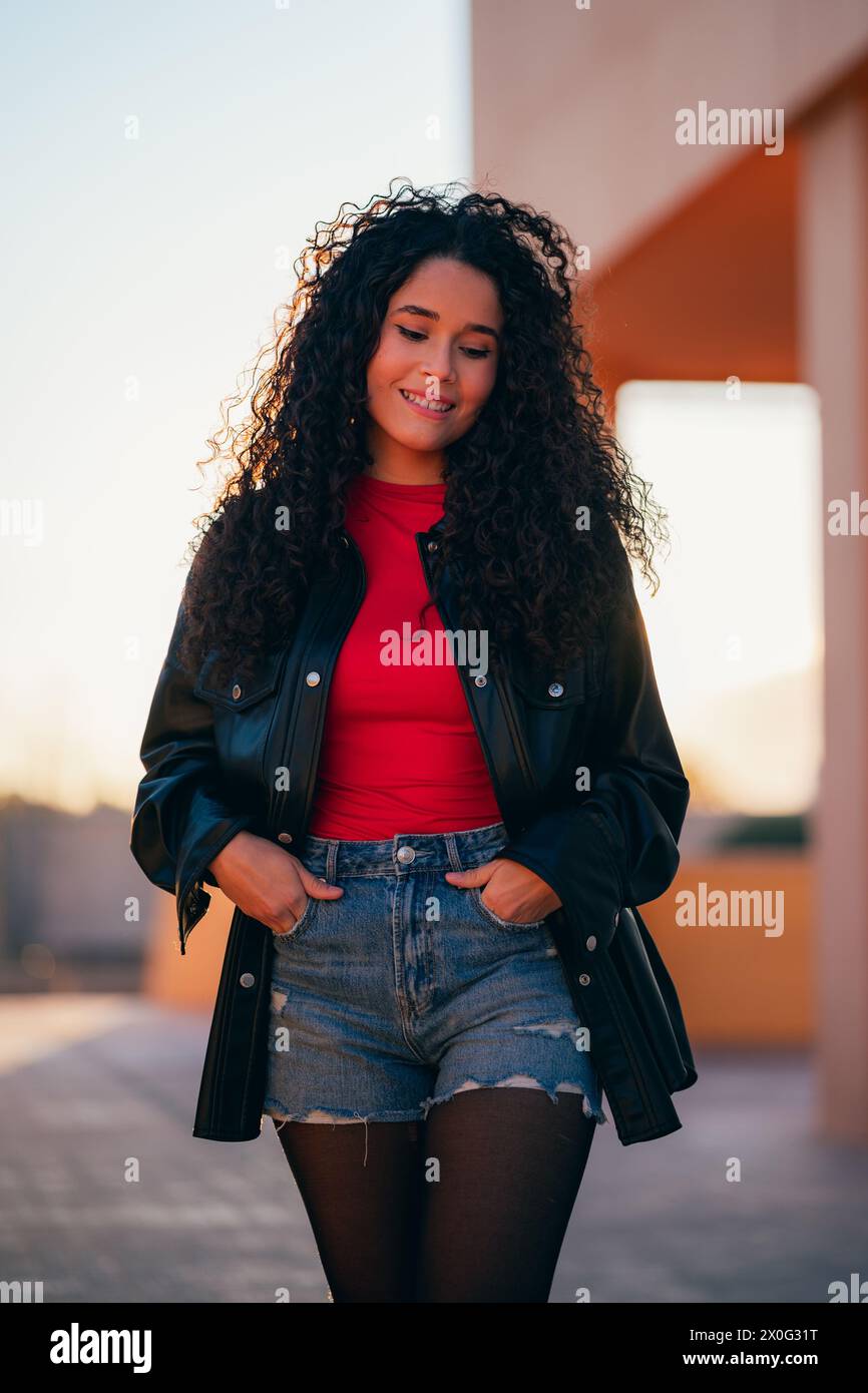 Curly-haired woman in red shirt and black jacket Stock Photo