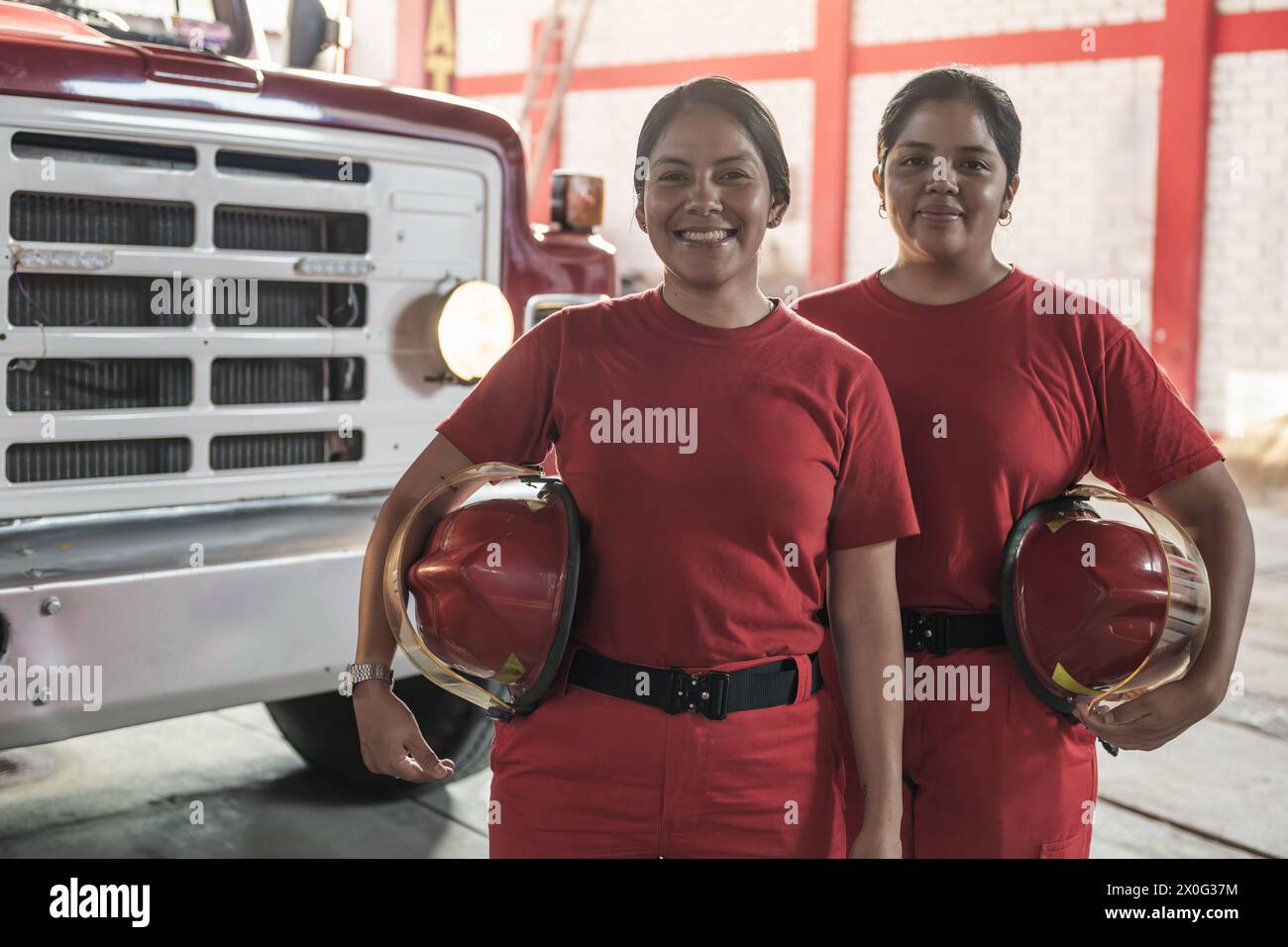 Portrait of happy female firefighters standing at fire station Stock Photo