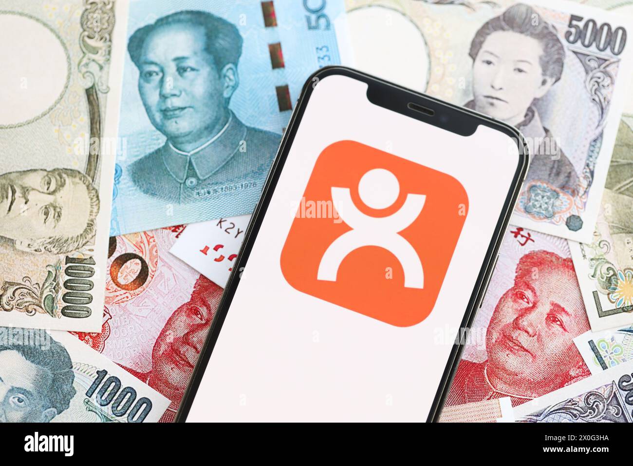 KYIV, UKRAINE - APRIL 1, 2024 Dianping platform icon on smartphone screen on many asian money bills. iPhone display with app logo with japanese yen and chinese yuan banknotes Stock Photo