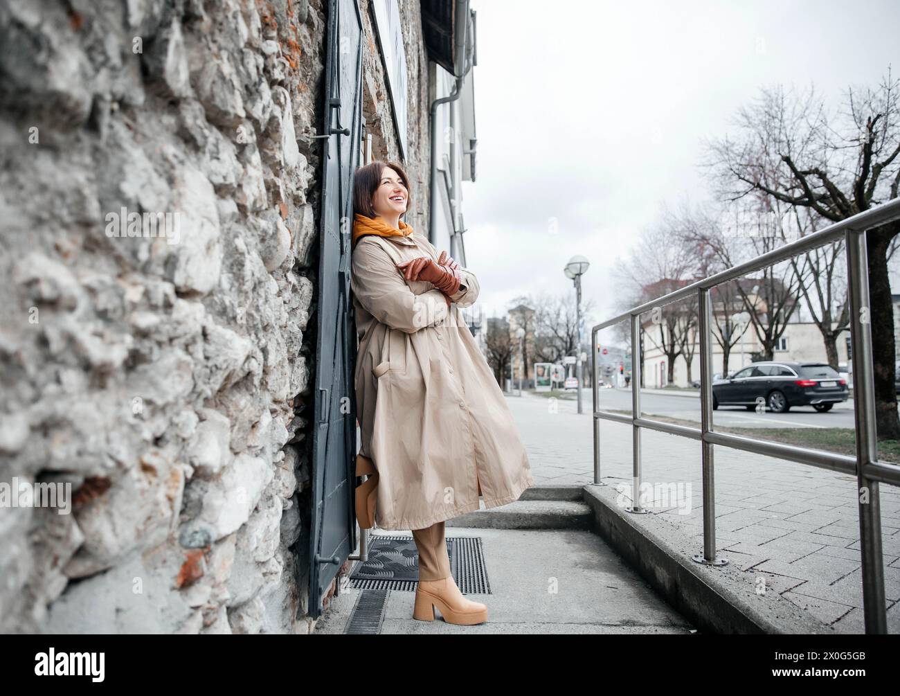 Joyful Woman in Trench Coat Embracing City Life on Street Corner Stock ...