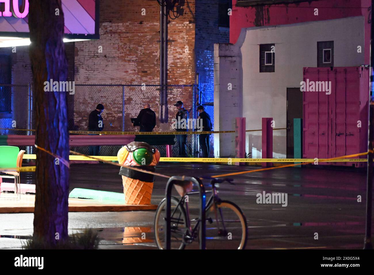 Police officers search for evidence at the crime scene where two people were shot leaving one of them critically wounded. Two people shot as they stood on a sidewalk in Chicago, Illinois, United States on April 12, 2024. At approximately 1:58 a.m., Friday morning two male adults were standing on the sidewalk on the 1800 block of S. Blue Island Avenue when a white vehicle approached from the alley and a suspect fired gunshots in their direction and then fled the scene. A 31-year-old male sustained a gunshot wound to the back and was transported to the hospital in critical condition, a 25-year-o Stock Photo
