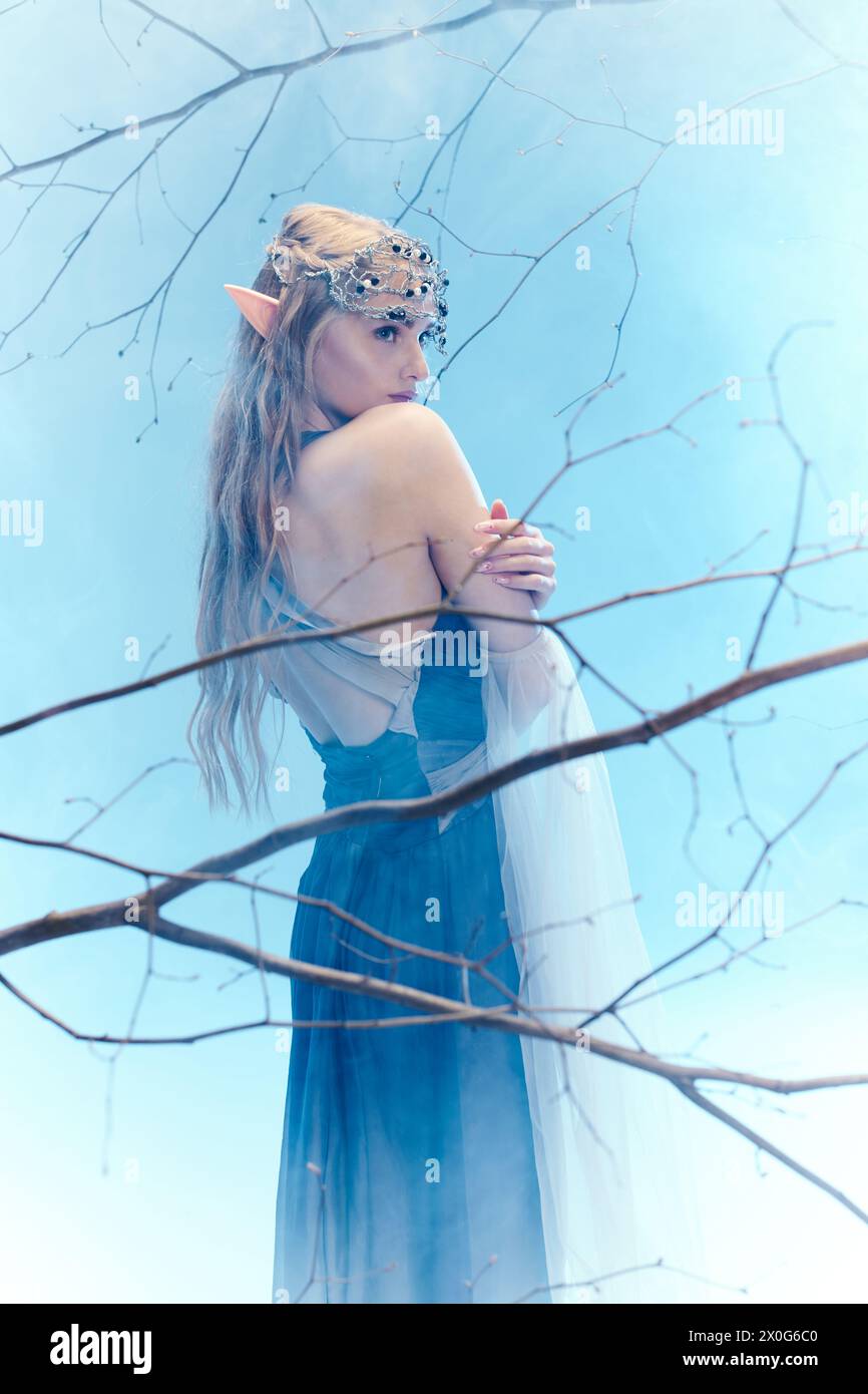 A young woman in a blue dress, resembling an elf princess, stands ...