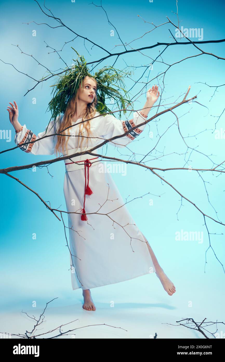 A young mavka in a traditional outfit holding branches in a magical studio setting. Stock Photo