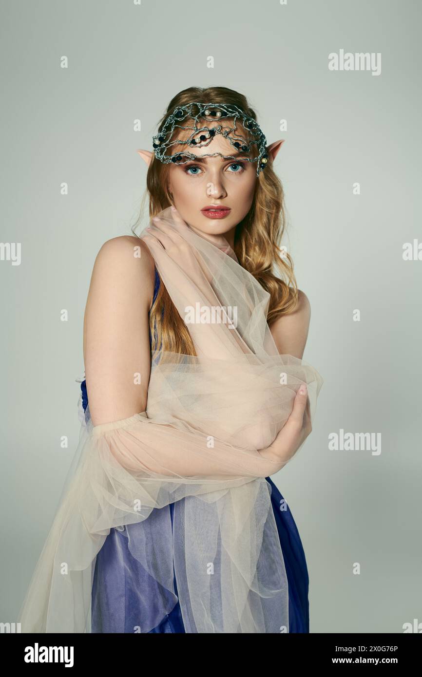 A young woman adorned in a veil and headpiece, embodying a fairy fantasy with an enchanting studio setting. Stock Photo