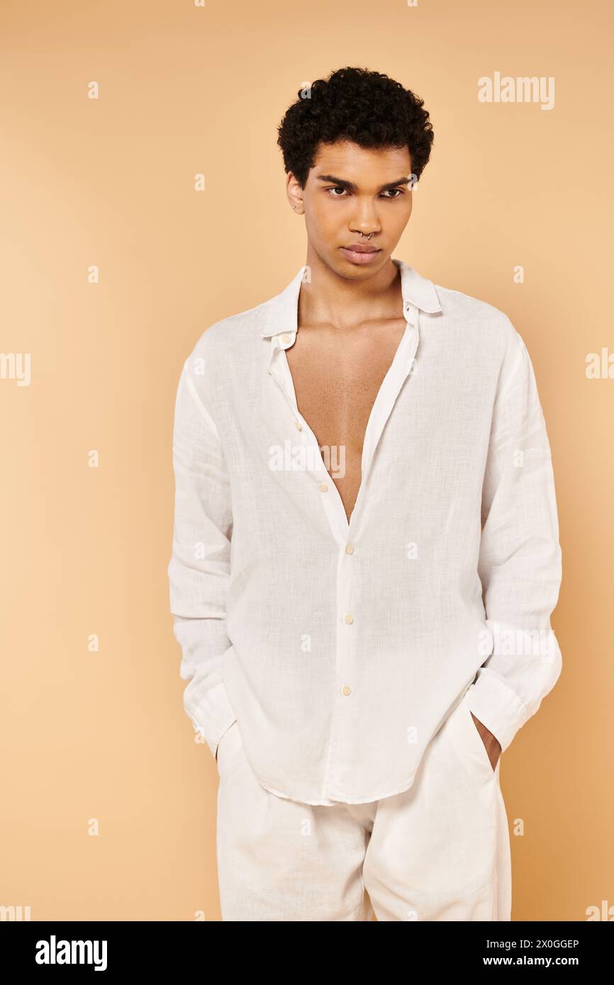 well dressed chic african american man in elegant white clothing looking away on beige backdrop Stock Photo