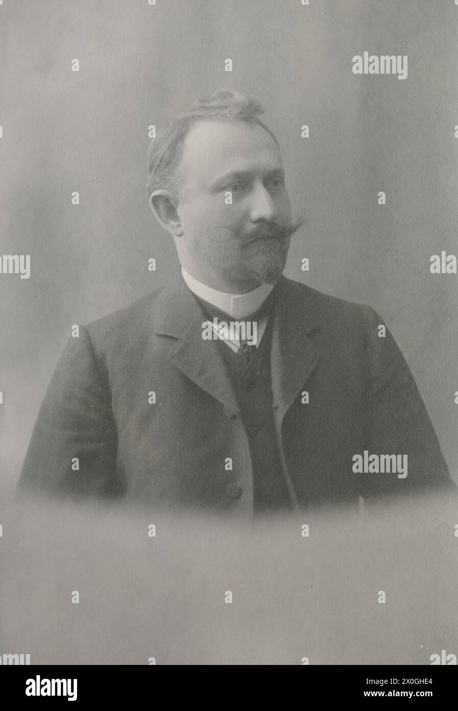 blond man, about 30 years old, with dark jacket and vest, white stiff ...
