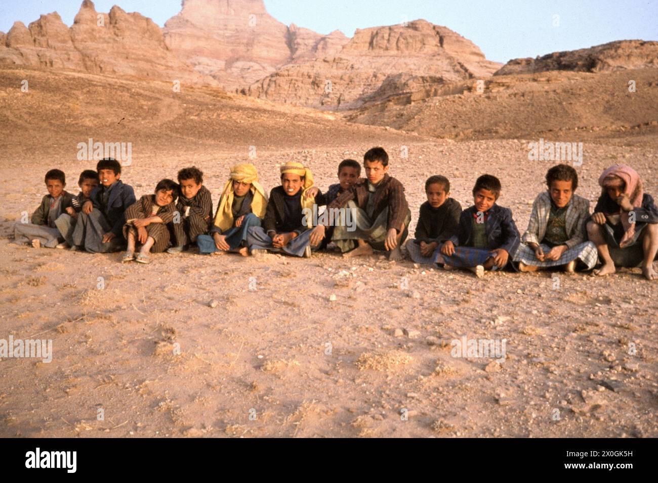A group of children sit in a row at a campground in Wadi Beni Husseisch in Yemen. [automated translation] Stock Photo