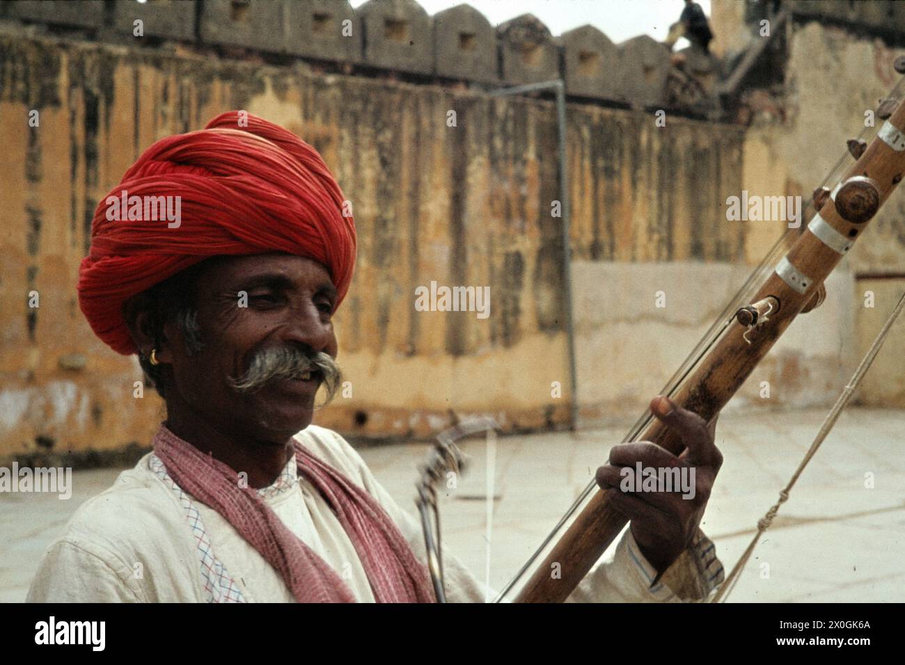 An elderly man with a red turban plays sitar in the palace courtyard in Amber. [automated translation] Stock Photo