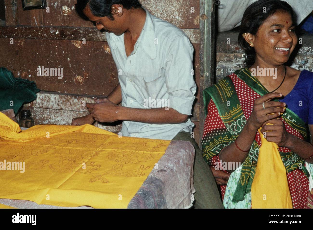 A man and a woman print patterns on yellow textiles in a fabric printing shop in Ahmedabad. [automated translation] Stock Photo