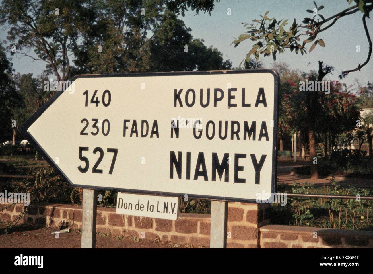 A street sign in Ouagadougou indicates the direction and distance to the towns of Koudela, Fada N'gourma and Niamey. [automated translation] Stock Photo
