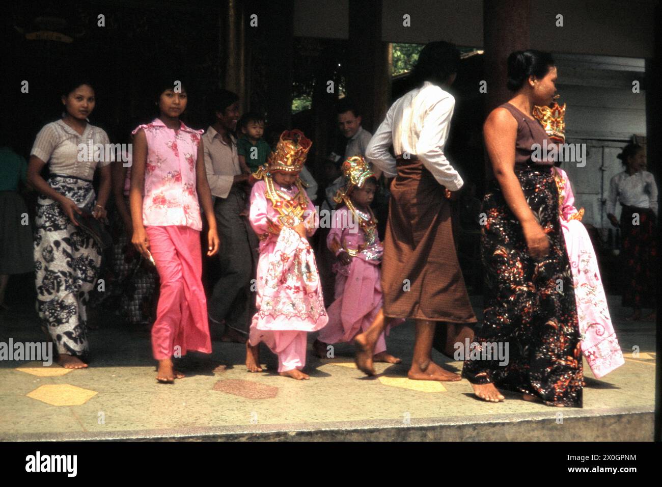 Eine burmesische Familie in zeremonieller Kleidung beim Verlassen der Mahamuni-Pagode nach einer Zeremonie in Mandalay. Stock Photo