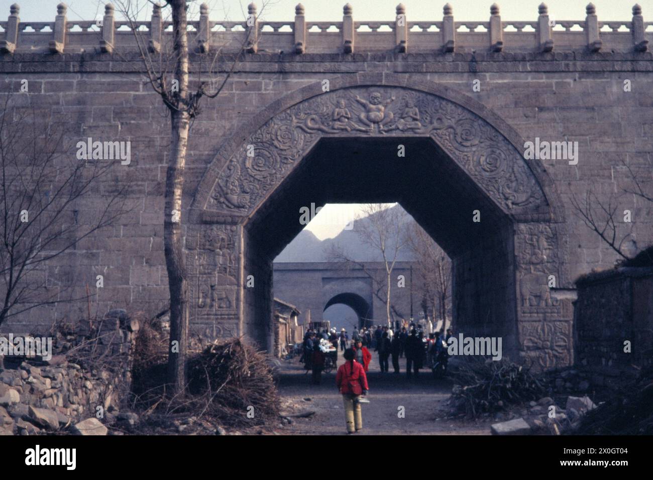 Tourists under a semi-hexagonal archway with reliefs at Juyong Pass. [automated translation] Stock Photo
