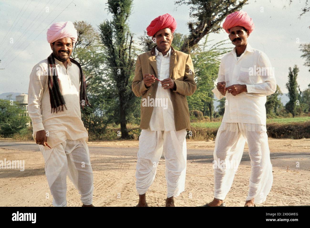 Three men with white clothes and red turbans on a street in Sadri ...