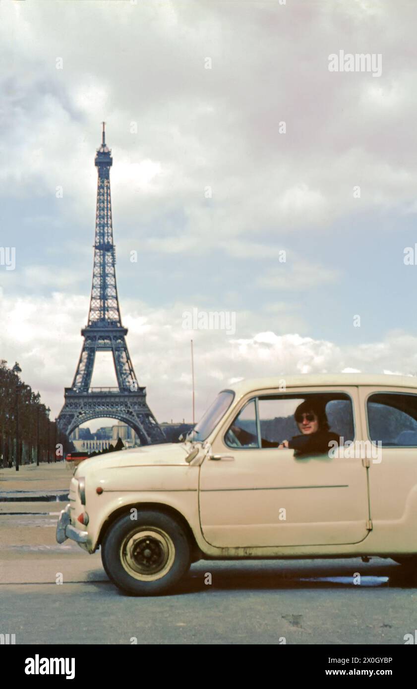 View of the Eiffel Tower in Paris. In front a young man in his Fiat 600. [automated translation] Stock Photo