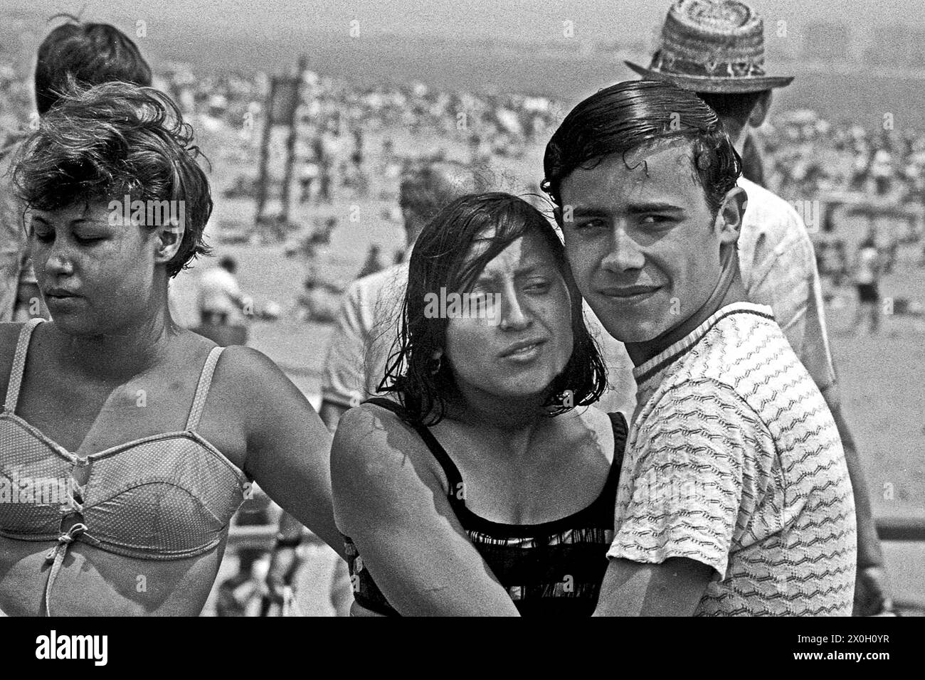 A couple is standing in front of a busy beach on Coney Island in New York. Stock Photo