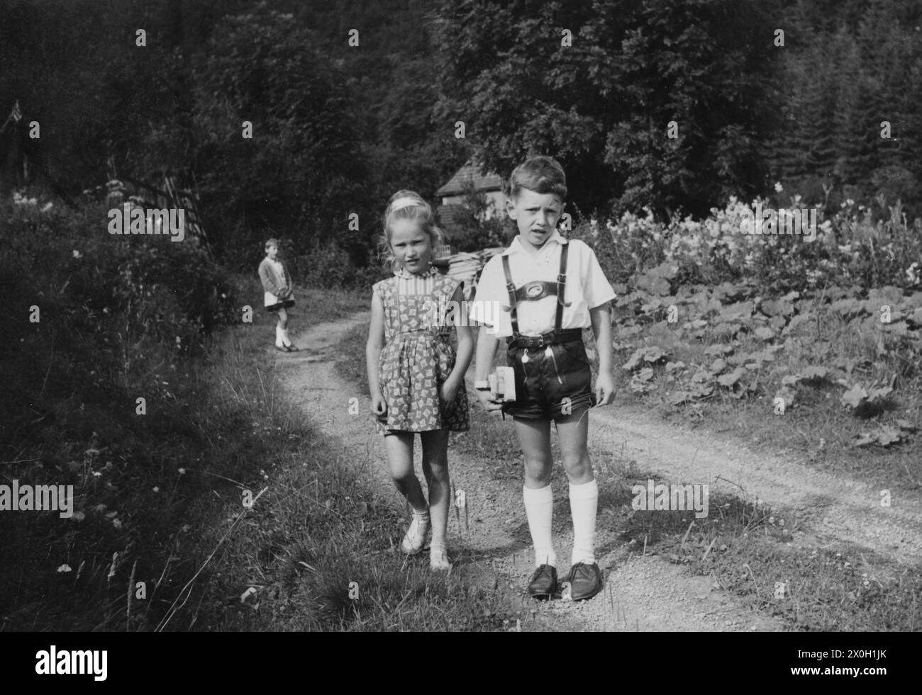 Three children, the boy with leather pants, during a walk in the Sauerland. Stock Photo