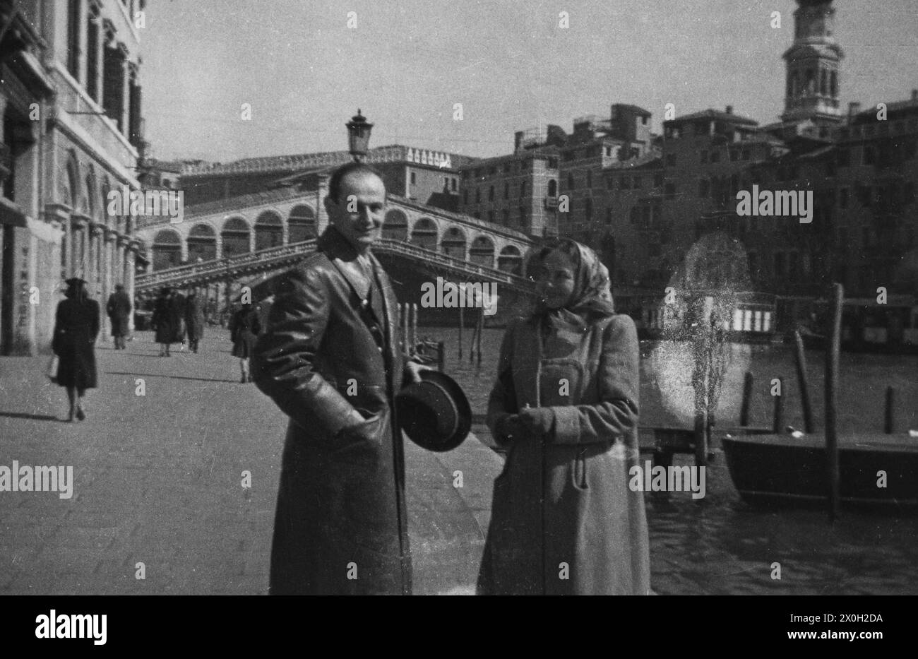 A couple, the woman with a headscarf and the man with hat, in front of the Rialto Bridge in Venice (undated picture). Stock Photo