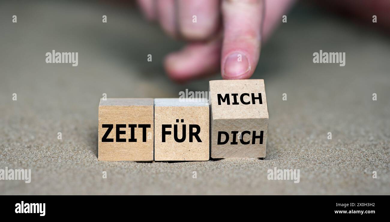 Hand turns cube and changes the German expression 'zeit für dich' (time for you) to 'zeit für mich' (time fo myself). Stock Photo