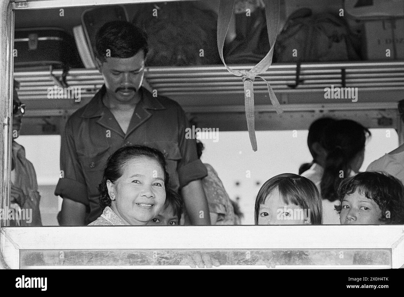 Am Bahnhof von Surat Thani in Thailand: Während der Vater noch Gepäck verstaut, sind Mutter und Kinder schon in Vorfreude auf die Reise auf ihren Plätzen. Stock Photo