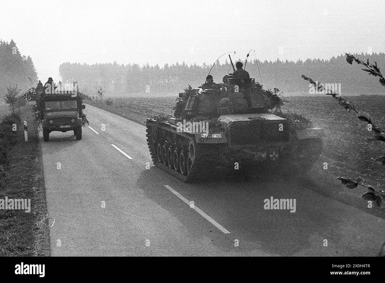 During a combat exercise, an off-road vehicle and a tank meet on a country road. [automated translation] Stock Photo