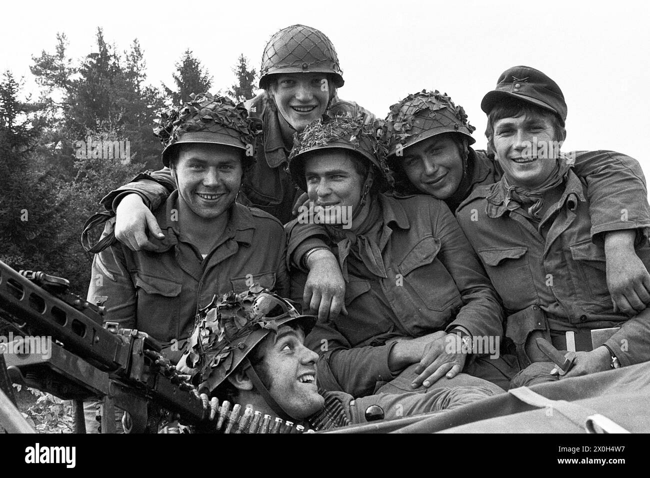During a military exercise of the II Corps of the German Armed Forces in the Swabian Alb, a troop of cheerful soldiers in uniform pose for the camera. They are wearing field suits and combat helmets. A machine gun can be seen on the left edge of the picture. [automated translation] Stock Photo