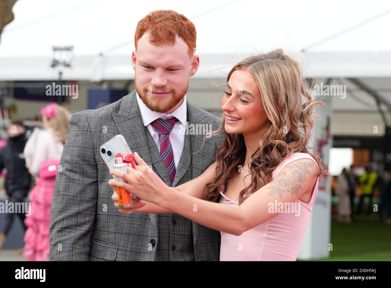 Aintree Racecourse, Aintree, Merseyside, England. 12th April 2024.  2024 Grand National Festival Day 2; A couple pose for a selfie during Ladies Day, day 2 of the festival.Photo credit: Stephen Hearn/Action Plus Sports Images/ Alamy Live News Stock Photo