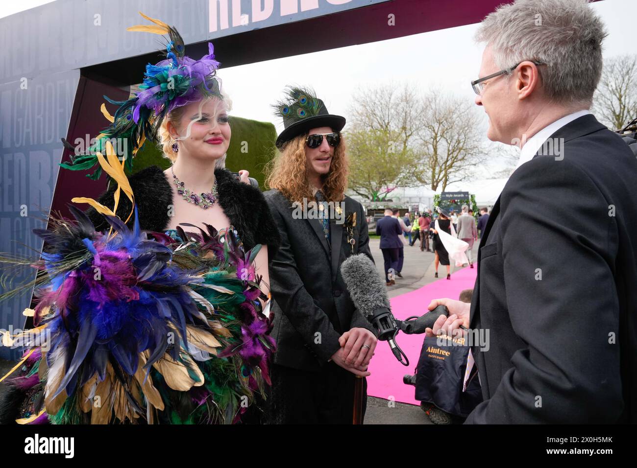 Aintree Racecourse, Aintree, Merseyside, England. 12th April 2024.  2024 Grand National Festival Day 2; Flamboyantly dressed race goers are interviewed during Ladies Day, day 2 of the festival.Photo credit: Stephen Hearn/Action Plus Sports Images/ Alamy Live News Stock Photo