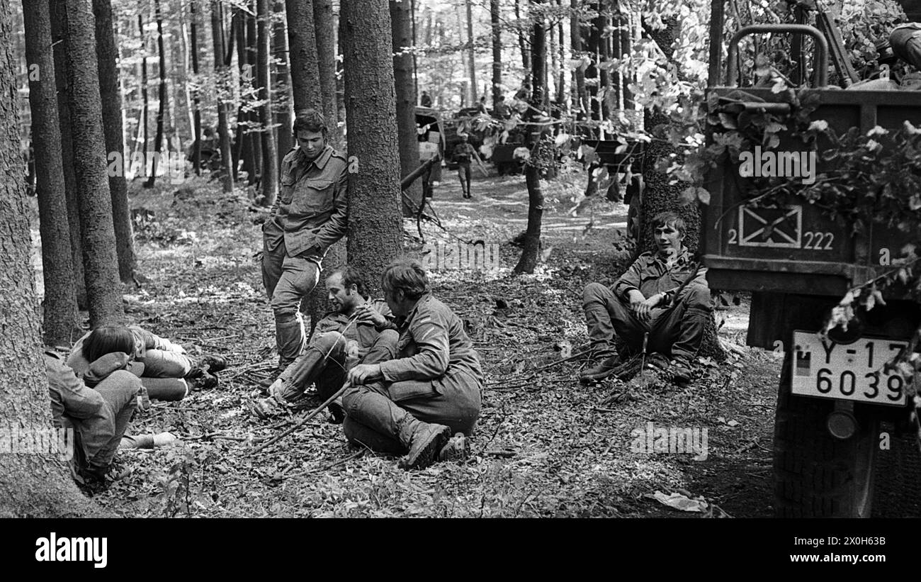During a military exercise of the II Corps of the German Armed Forces in the Swabian Alb, a group of uniformed soldiers, camouflaged under trees, wait for their next mission. Some soldiers are sitting or lying on the forest floor. Parts of an emergency vehicle, presumably a Unimog, can be seen on the right edge of the picture. [automated translation] Stock Photo