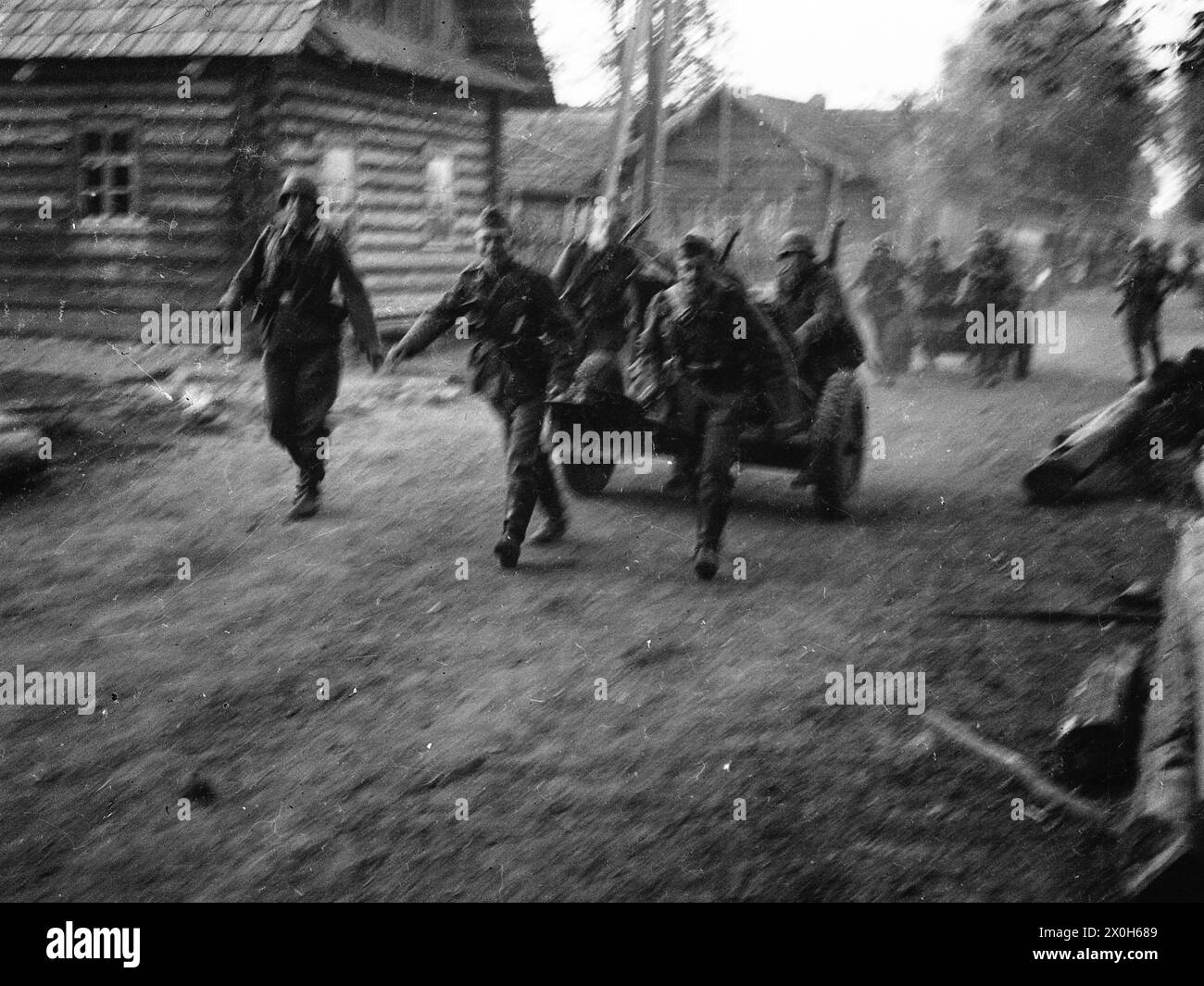In a village in the hinterland of the Eastern Front, German soldiers drag infantry guns along the dusty road. The picture was probably taken in connection with battles with partisans. The picture was taken by a member of the Radfahrgrenadierregiment 2, presumably in the middle section of the Eastern Front. [automated translation] Stock Photo