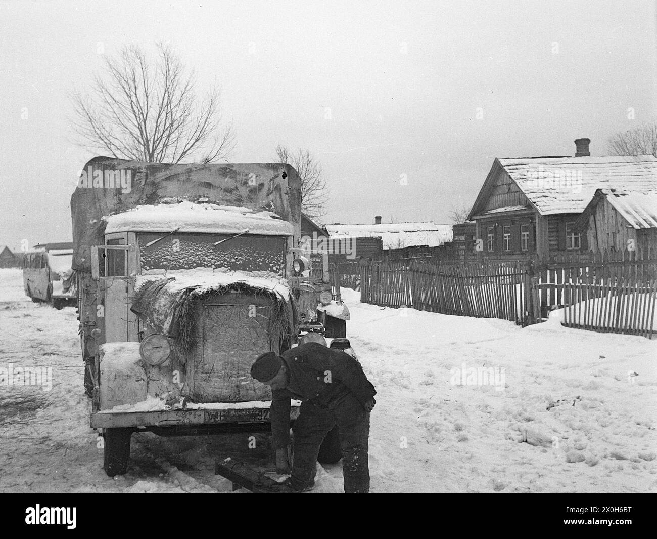 In order to start the car in the cold, a German soldier heats the engine and diesel fuel from below. The picture was taken by a member of the Radfahrgrenadierregiment 2 / Radfahrsicherungsregiment 2, in the northern section of the Eastern Front. [automated translation] Stock Photo