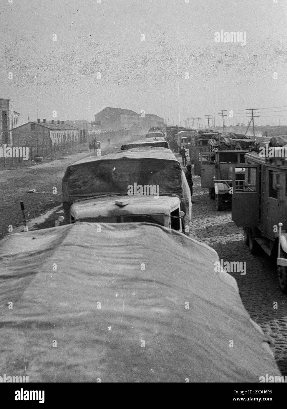 A long line of vehicles waits on a paved road to the loading station. They are loaded onto freight trains and driven towards the eastern front. The picture was taken by a member of the Radfahrgrenadierregiment 2 / Radfahrsicherungsregiment 2, on the Eastern Front. Presumably during the advance in the summer of 1941 [automated translation] Stock Photo