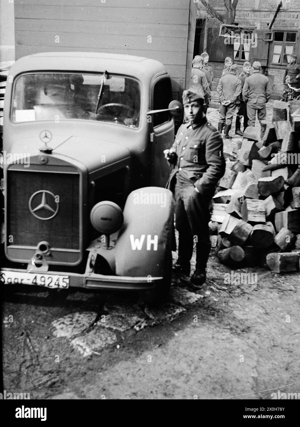 A driver with his Mercedes truck on a farm. Other soldiers in the background. The picture was taken by a member of the 154th Infantry Regiment / 58th Infantry Division, in France. [automated translation] Stock Photo