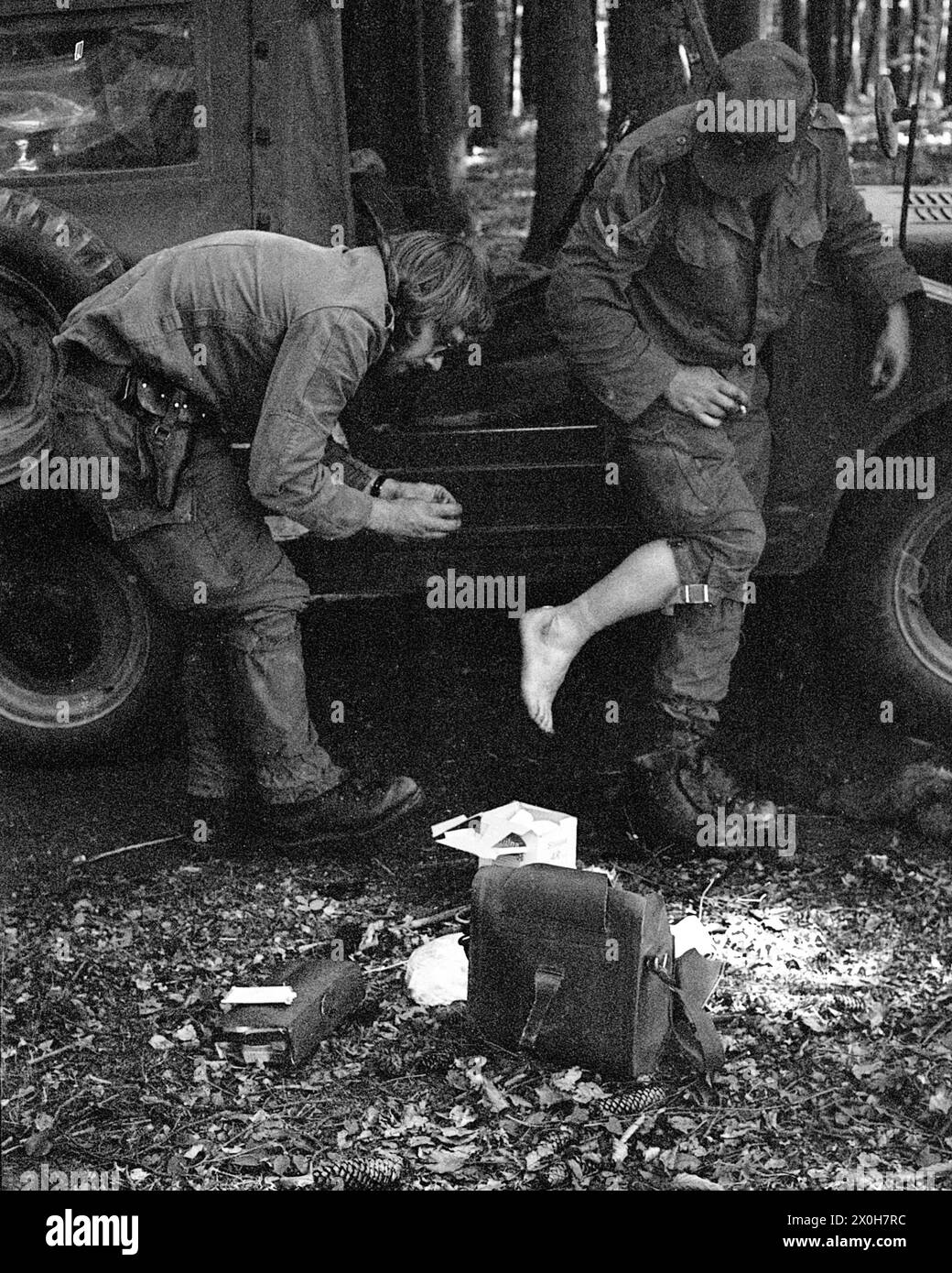 During a military exercise of the II Corps of the German Armed Forces in the Swabian Alb, a medic treats another soldier in uniform. The latter has blistered his feet. Medical equipment lies on the ground. Parts of a truck can be seen in the background. [automated translation] Stock Photo