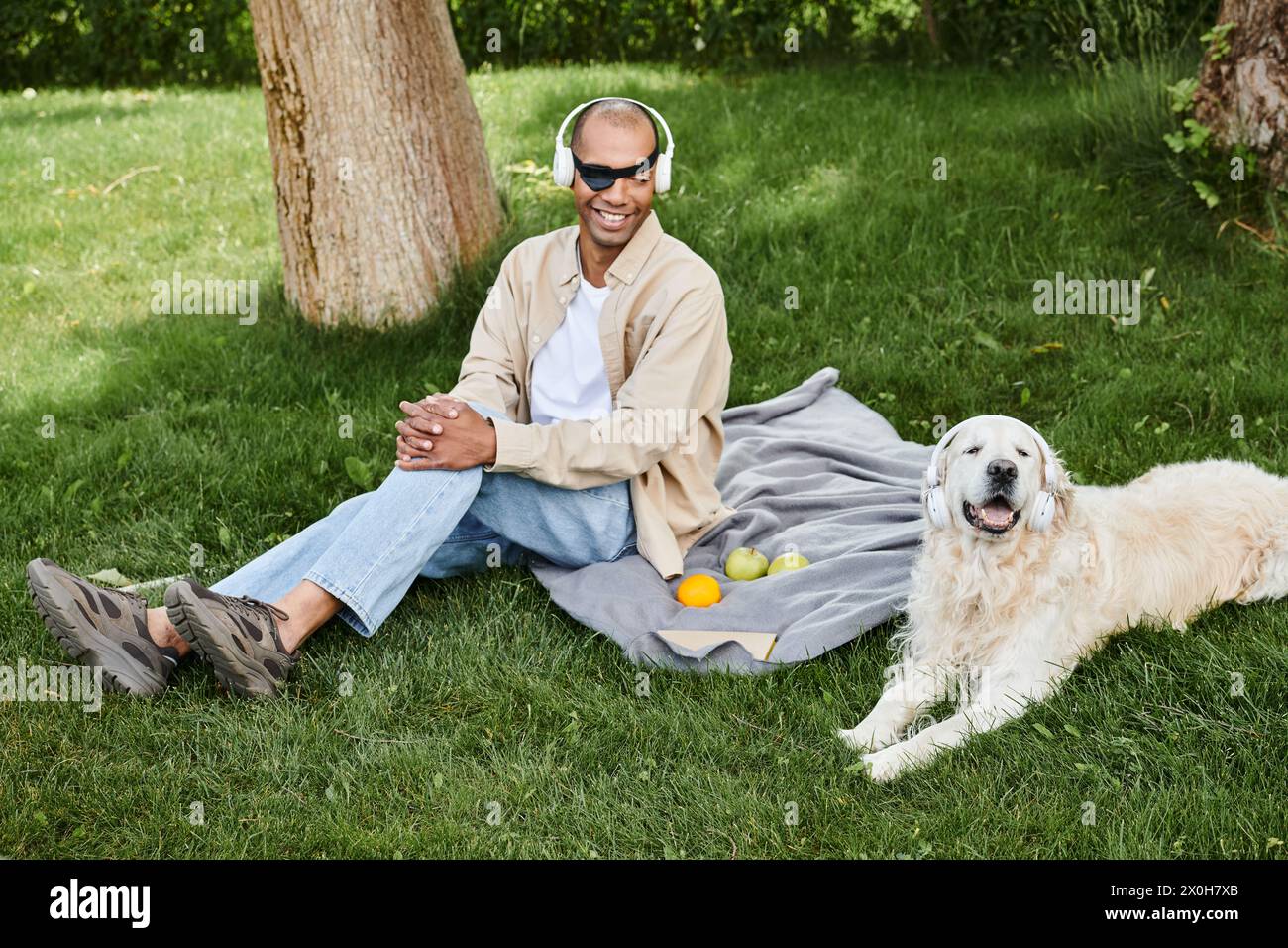 A man with myasthenia gravis syndrome sits on a blanket next to his loyal Labrador dog, lost in thought. Stock Photo