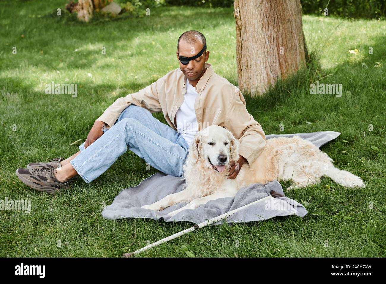 A man with myasthenia gravis sits in the grass, reflecting with his two dogs, showcasing