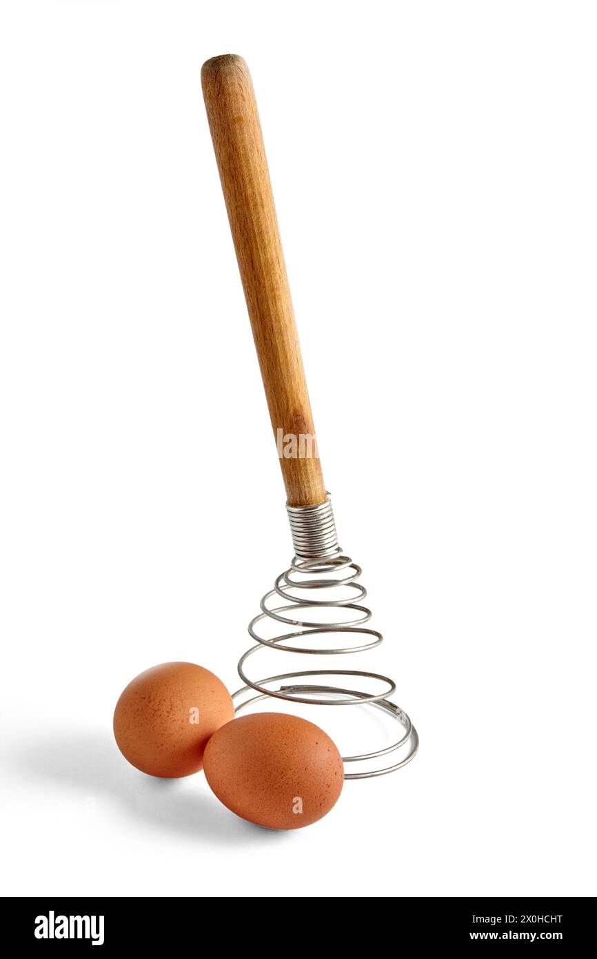 Two beige chicken eggs and a spiral metal whisk are isolated on a white background Stock Photo