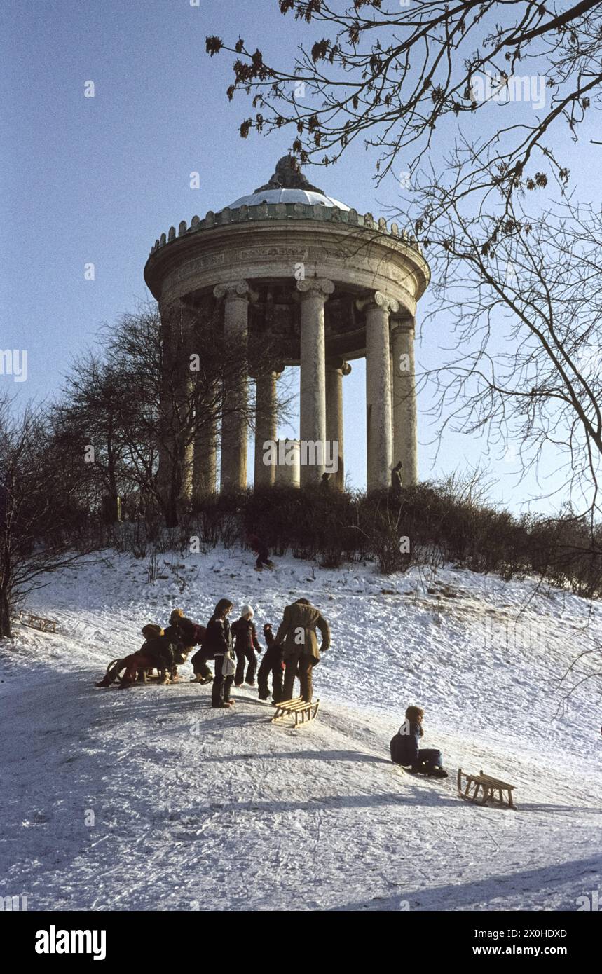 Children and adults toboggan in the afternoon sun in the English Garden