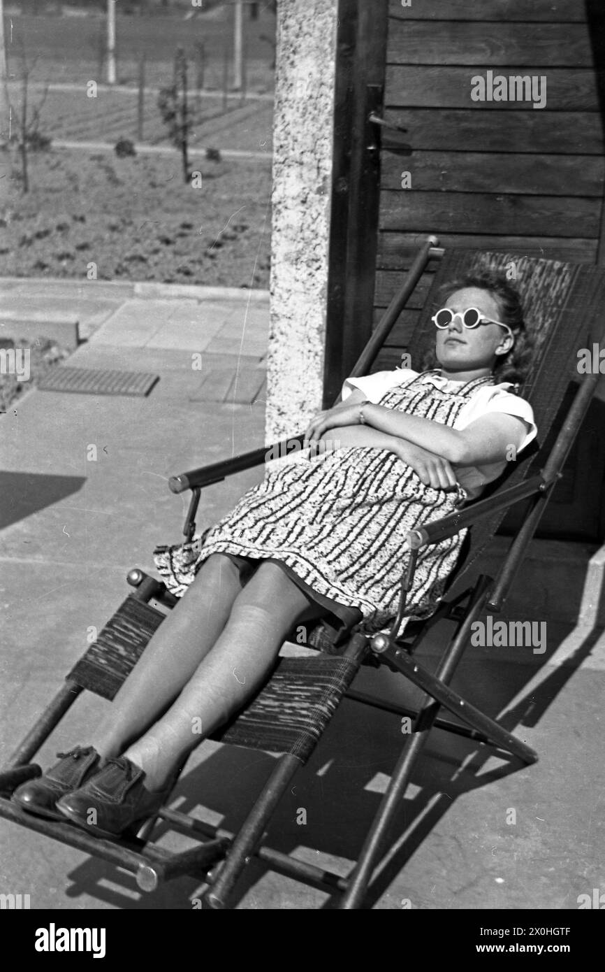 A young woman with sunglasses sunbathing in a deck chair. Stock Photo