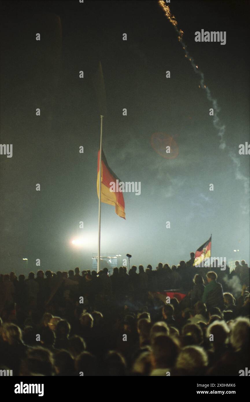 Eine Menschenmenge feiert in der Nacht auf den 3. Oktober die deutsche Wiedervereinigung vor dem Reichstagsgebäude in Berlin. Stock Photo
