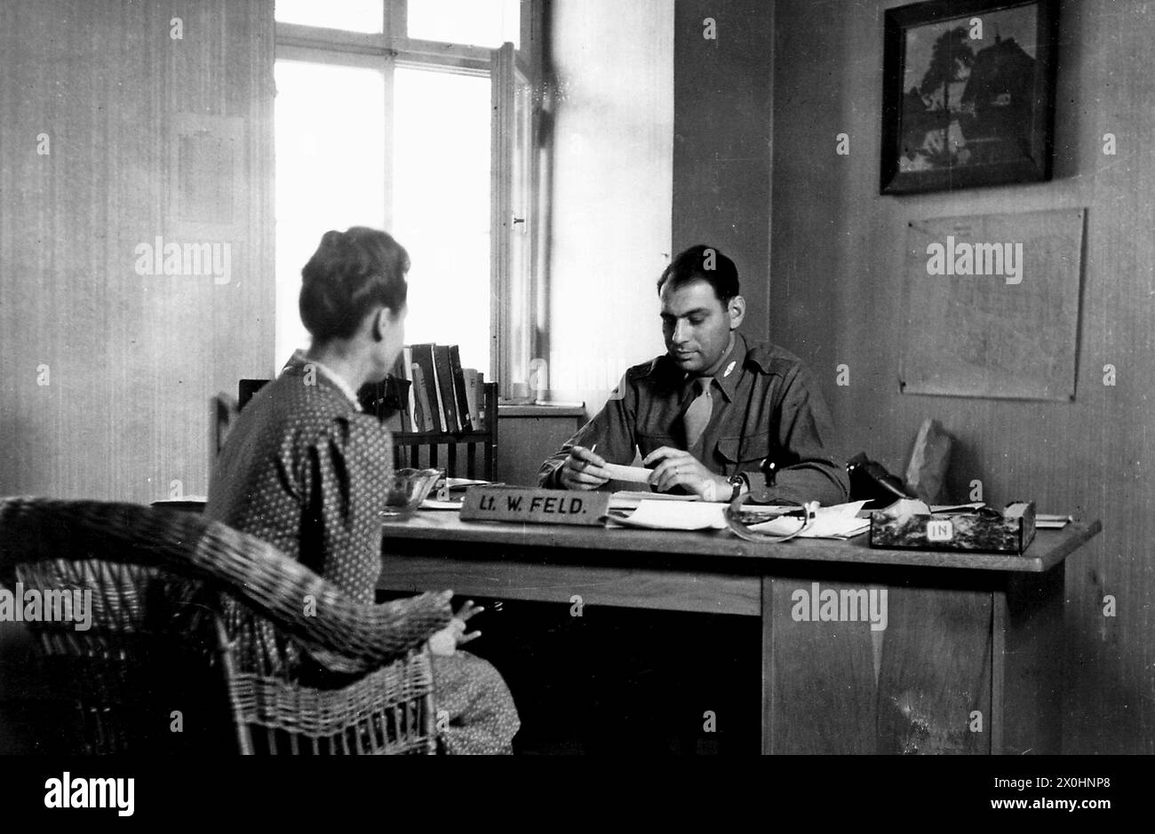 The American Lieutenant Feld in conversation with a young German woman at his desk in an office in Ochsenfurt - presumably an application for employment as a clerk in the American military. [automated translation] Stock Photo