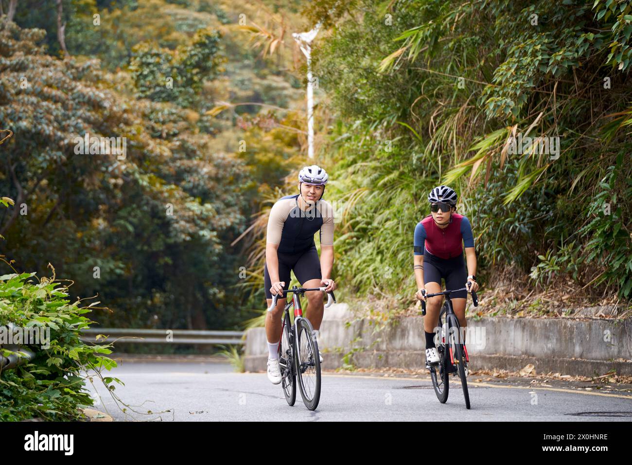 young asian couple cyclists riding bike on rural road Stock Photo