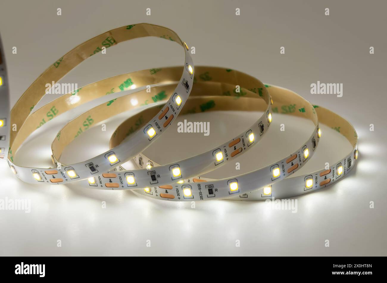 Discover versatility of modern lighting with illuminated LED strip light coils. White glowing LED tape, arranged in circular shapes, showcases flexibi Stock Photo