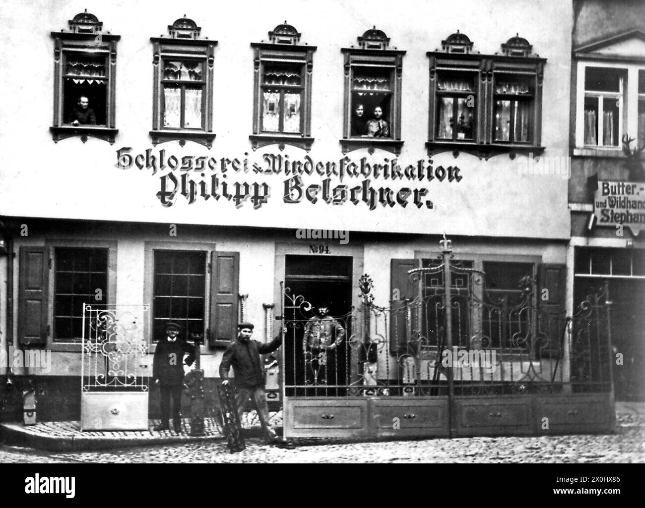 Locksmith and winch store. Workers with their products. To the right butter and game store [automated translation] Stock Photo