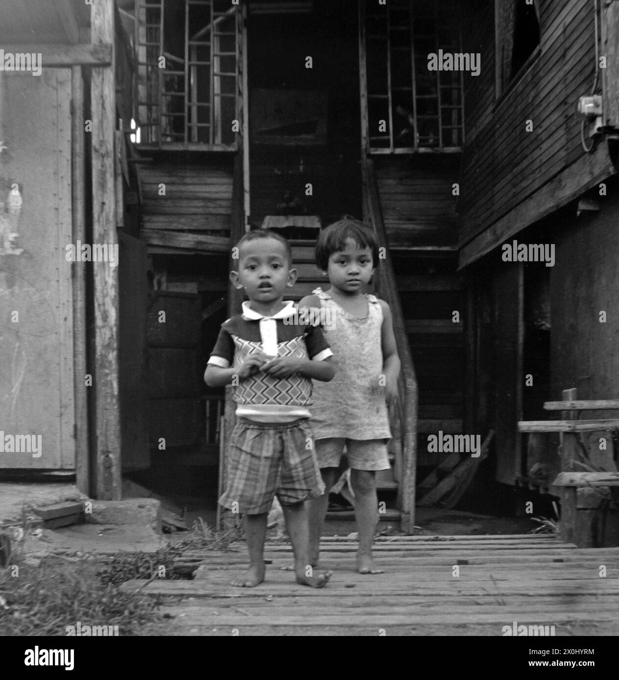 Two small children stand in Pagsanjan in the Philippines in front of the stairs to a wooden house. [automated translation] Stock Photo