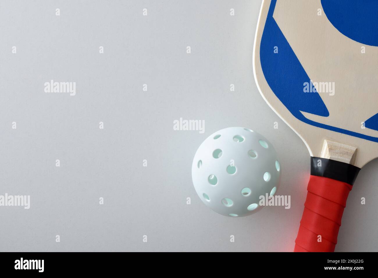 Detail of pickleball racket and a white ball isolated on white table. Top view. Stock Photo