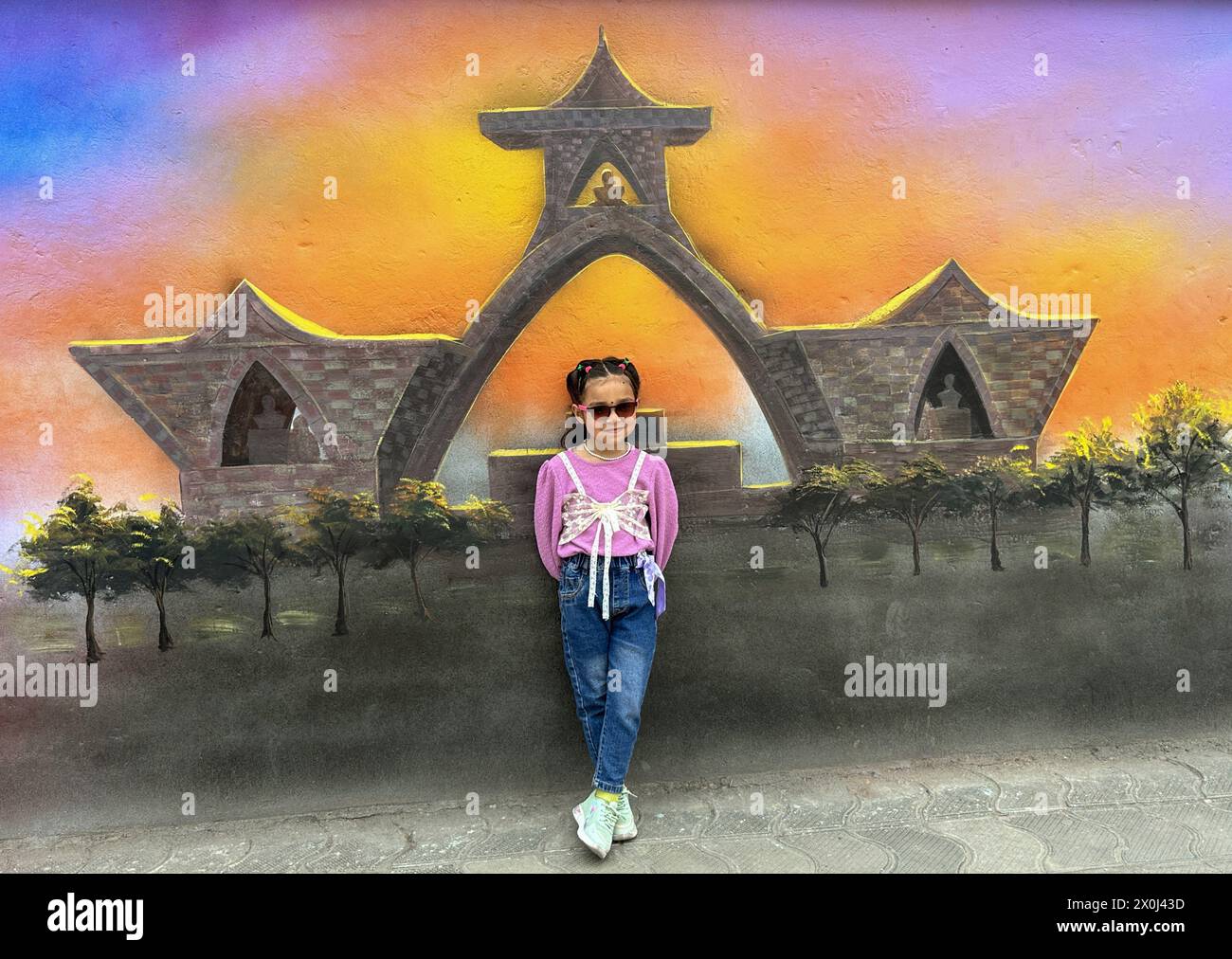 Kathmandu, Nepal. April 12, 2024: A small girl pose in front of a mural art in Kathmandu, Nepal on April 12, 2024. Artists paint a mural, showcasing Nepal's vibrant culture, tradition, portraits & festivals to decorate the walls of capital city. (Credit Image: © Sunil Sharma/ZUMA Press Wire/Alamy Live News) EDITORIAL USAGE ONLY! Not for Commercial USAGE! Stock Photo